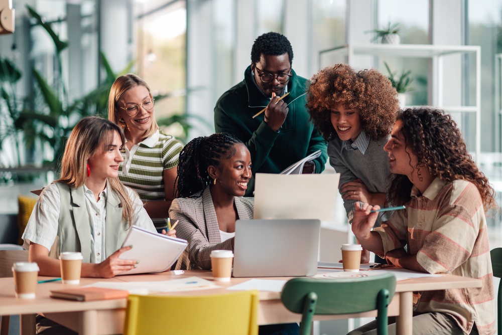 Diverse agency team collaborating around a laptop in a bright office