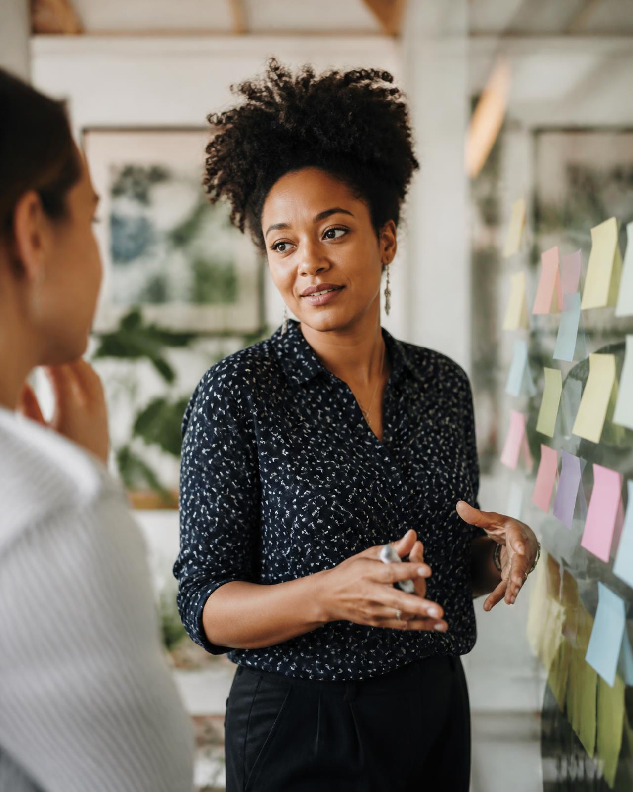 A content strategist planning a campaign on a glass wall of notes with a teammate